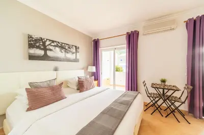 a bedroom with a large white bed with purple curtains at Oasis Beach Apartments in Luz