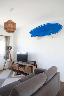 a living room with a couch and a surfboard on the wall at Casa Biota in Sagres