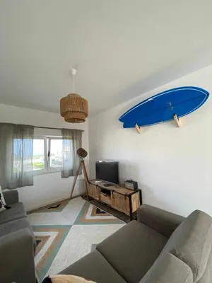 a living room with a couch and a surfboard on the wall at Casa Biota in Sagres