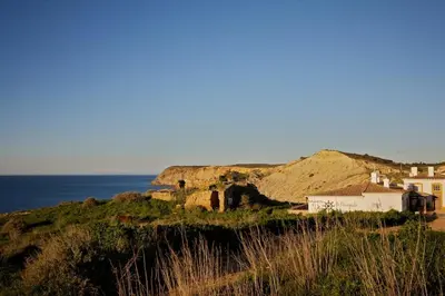 a house on top of a hill next to the ocean at Apartamentos Os Descobrimentos in Burgau