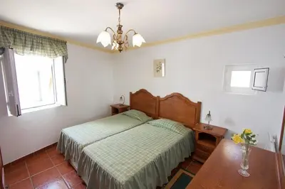 a bedroom with a bed with a green bedspread and a window at Apartamentos Os Descobrimentos in Burgau