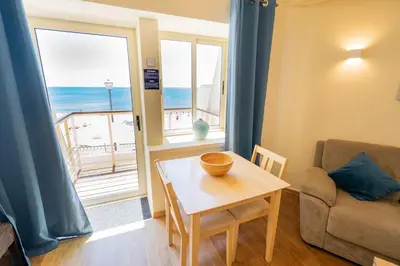 a living room with a table and a view of the ocean at Luz Beach Apartments in Luz
