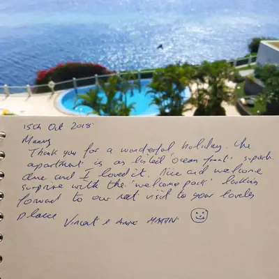 a handwritten letter on a sign with the ocean in the background at Oceanfront Apartment in Funchal