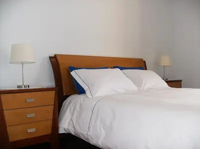 a bedroom with a bed and a nightstand with two lamps at Oceanfront Apartment in Funchal