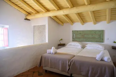 a bedroom with two beds and a wooden ceiling at Aldeia da Pedralva by WOT Signature in Vila do Bispo