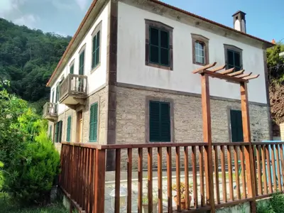 an old stone house with a wooden fence at Quinta do Serrado in Porto Moniz