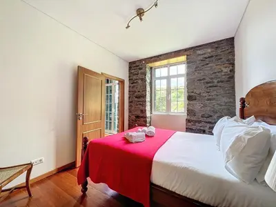 a bedroom with a large bed with a red blanket at Quinta do Serrado in Porto Moniz
