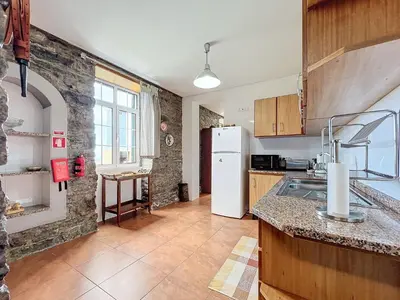 a kitchen with a white refrigerator and a table at Quinta do Serrado in Porto Moniz