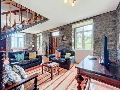a living room with leather furniture and stone walls at Quinta do Serrado in Porto Moniz