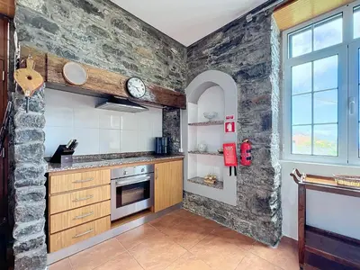 a kitchen with a stone wall at Quinta do Serrado in Porto Moniz