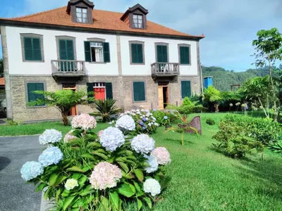 a house with a bunch of flowers in the yard at Quinta do Serrado in Porto Moniz