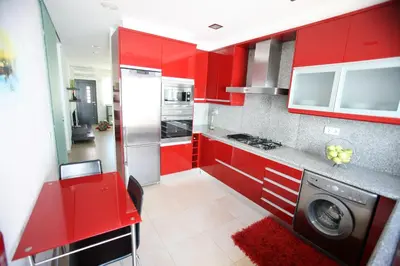 a red kitchen with a washing machine in it at Luz House in Luz