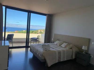 a bedroom with a bed with a view of the ocean at Villa Pinheira I in Calheta