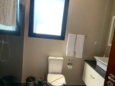 a bathroom with a toilet and a sink and a window at Villa Pinheira I in Calheta