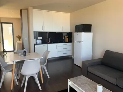 a living room with a couch and a table and a kitchen at Villa Pinheira I in Calheta