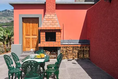 a patio with a table and chairs and a pizza oven at Casa da Aldeia by An Island Apart in Câmara de Lobos