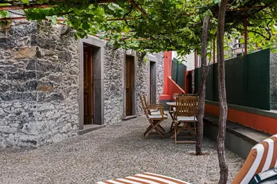 a patio with chairs and a table next to a building at Casa da Aldeia by An Island Apart in Câmara de Lobos