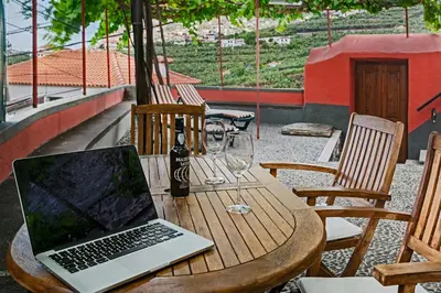 a laptop computer sitting on a wooden table with wine glasses at Casa da Aldeia by An Island Apart in Câmara de Lobos
