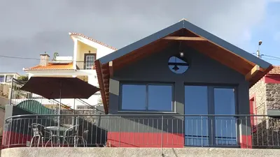 a house with a balcony with a table and an umbrella at Adega do Avô 2 Madeira in Estreito da Calheta