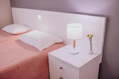 a bed with a nightstand with a lamp and flowers on it at Funchal City Apartments in Funchal