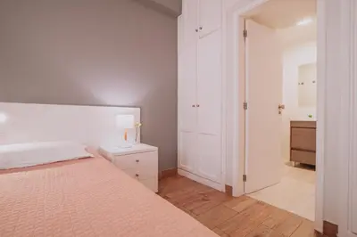 a white bedroom with a large bed and a dresser at Funchal City Apartments in Funchal