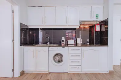 a kitchen with white cabinets and a washing machine at Funchal City Apartments in Funchal