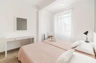 a white bedroom with a bed and a tv at Funchal City Apartments in Funchal