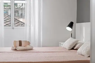 a white bedroom with a bed with two pillows and a lamp at Funchal City Apartments in Funchal