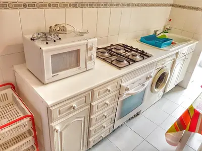 a kitchen with a stove and a microwave at Falesia Apartment - Reis Magos Beach in Caniço