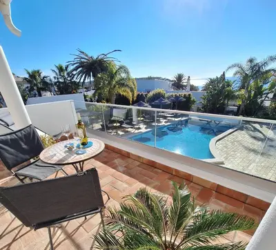 a balcony with a table and a view of a swimming pool at Romantik Villa in Salema