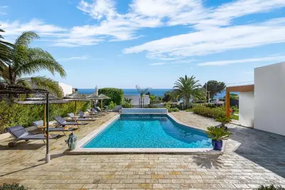 a swimming pool in a yard with chairs and the ocean at Romantik Villa in Salema