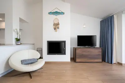 a living room with a white chair and a tv at Romantik Villa in Salema
