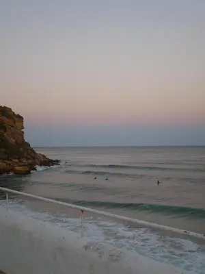 a beach with some surfers in the water and the ocean at Aloha Burgau Guesthouse in Burgau