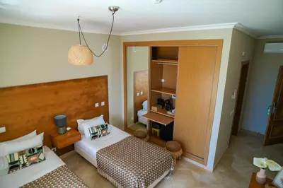 a hotel room with two beds and a bathroom at Arrifana Destination Suites in Aljezur
