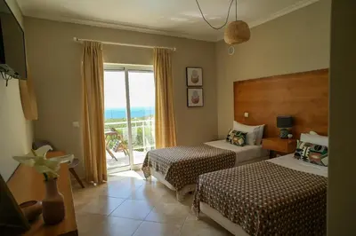 a hotel room with two beds and a balcony at Arrifana Destination Suites in Aljezur