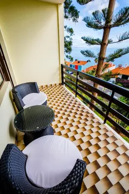 a balcony with chairs and tables and a palm tree at Studio Oceano in Caniço