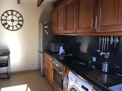 a kitchen with wooden cabinets and a clock on the wall at Villa Atlantis in Calheta