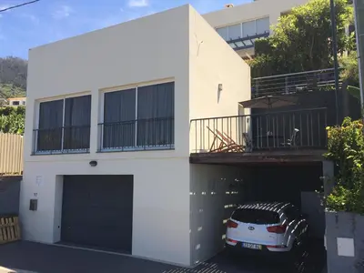 a white house with a car parked in the garage at Villa Atlantis in Calheta