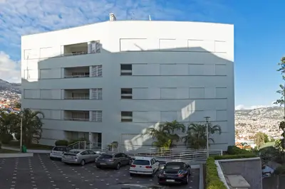a white building with cars parked in a parking lot at Jasmineiro II by An Island Apart in Funchal