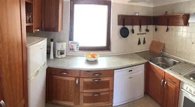 a small kitchen with wooden cabinets and a sink at Casa Matschinegg Madeira in Caniço