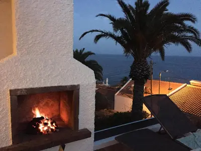 a fireplace on the side of a house with a palm tree at Casa Matschinegg Madeira in Caniço