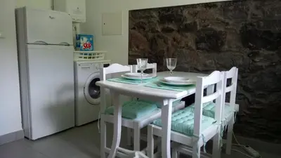 a kitchen with a white table with chairs and a refrigerator at Casa da Ribeira in São Vicente