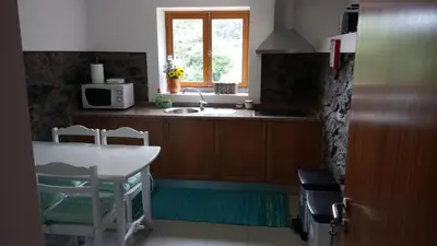 a kitchen with a table and a sink and a window at Casa da Ribeira in São Vicente