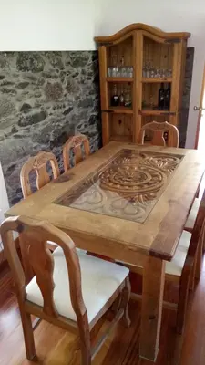 a wooden table with four chairs and a wooden cabinet at Casa da Ribeira in São Vicente