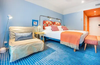a blue room with two beds and a chair at Pestana Casino Studios in Funchal