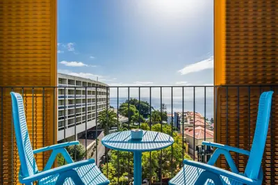 a balcony with two chairs and a table with a view of the ocean at Pestana Casino Studios in Funchal