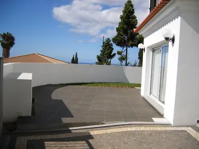 a white building with a walkway next to a fence at Vila Faia in Caniço