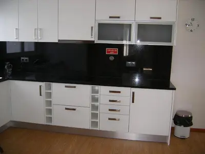 a kitchen with white cabinets and a black counter top at Vila Faia in Caniço