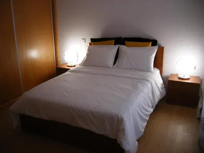 a bedroom with a large white bed with two lamps at Vila Faia in Caniço