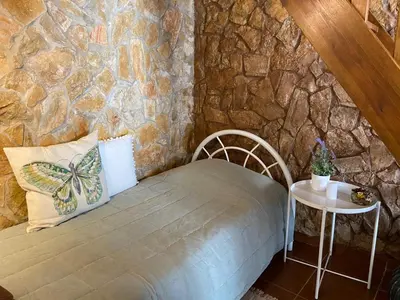 a stone walled room with a bed and a table at Casa Alfarroba in Barão de São Miguel